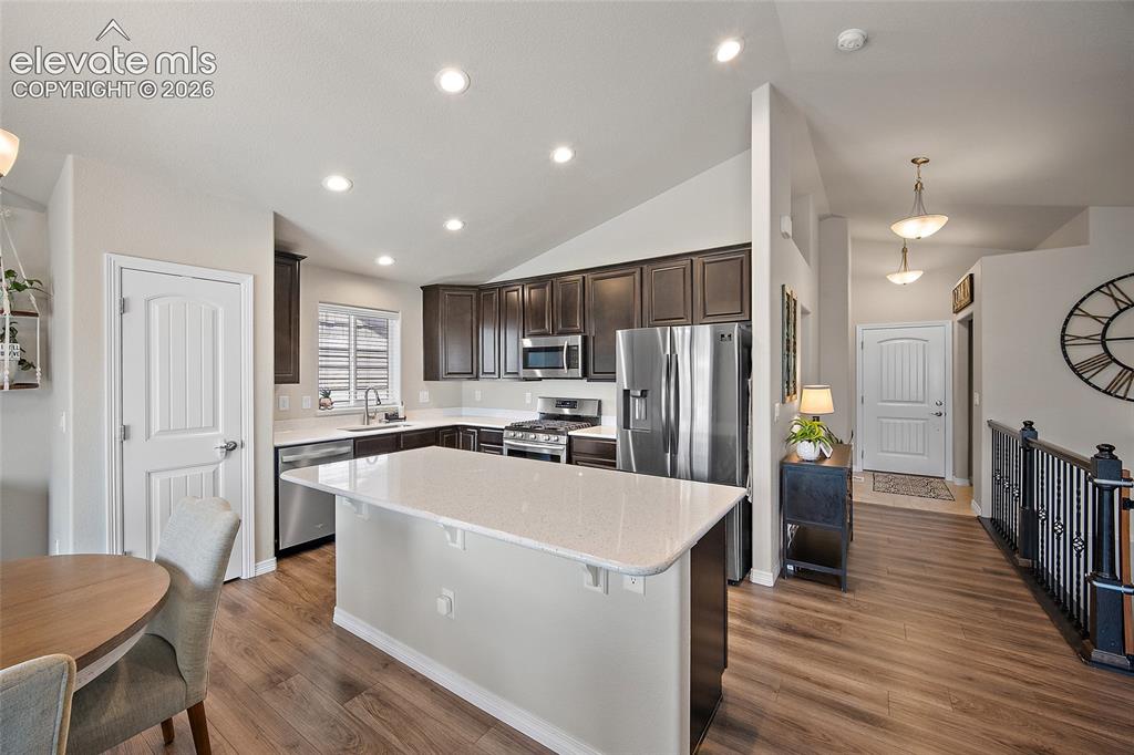 Image 2 of 49: Kitchen featuring dark wood cabinetry, stainless steel appliances, a white