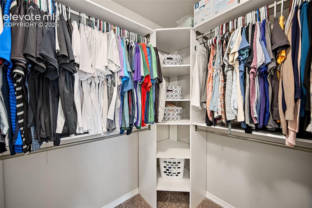 Image 21 of 50: Customizable closet system featuring multiple hanging rods, corner shelving