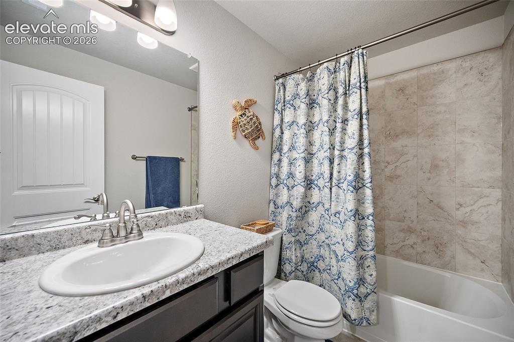 Image 24 of 49: Bathroom with a white oval sink, speckled countertop, dark wood-finish cabi