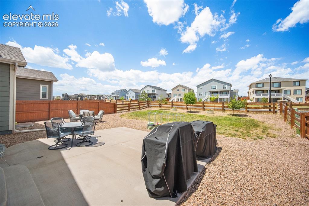 Image 34 of 49: Rear patio with concrete surface, surrounded by gravel and a wooden privacy