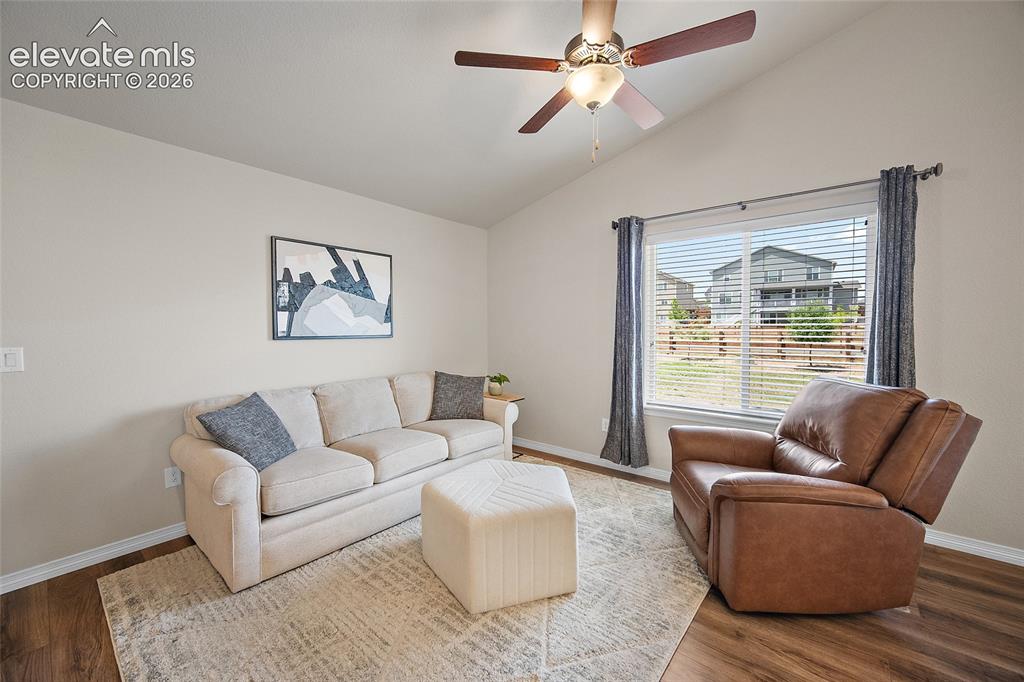 Image 4 of 49: Vaulted ceiling living area featuring wood-finish flooring, a large window