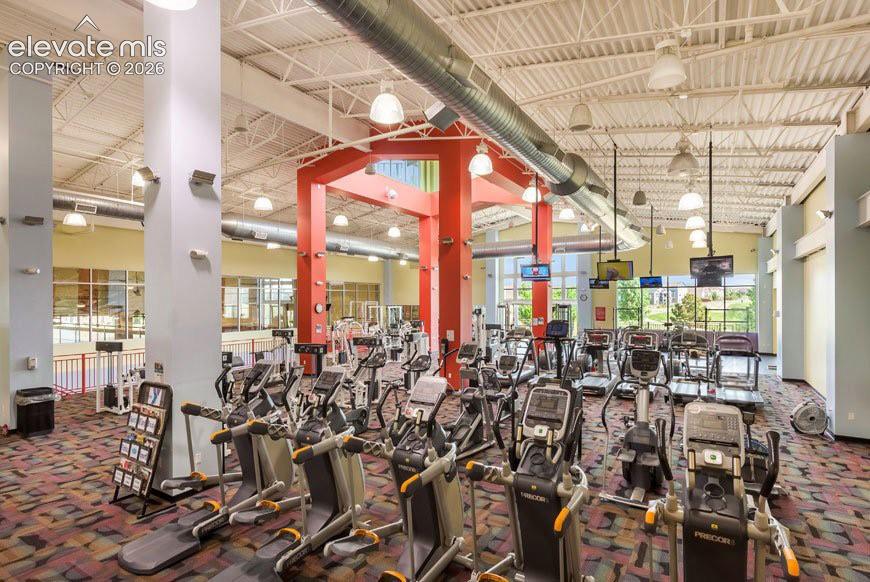 Image 40 of 49: Spacious fitness center featuring various cardio machines, exposed industri