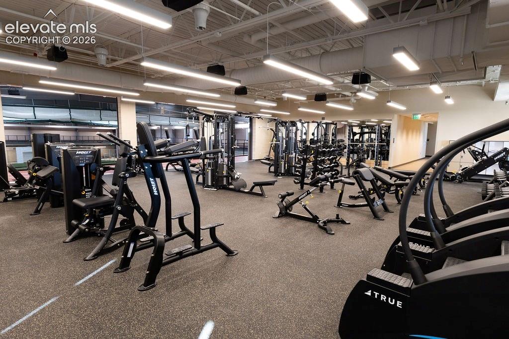 Image 44 of 49: Spacious fitness center featuring rubberized flooring, abundant natural lig