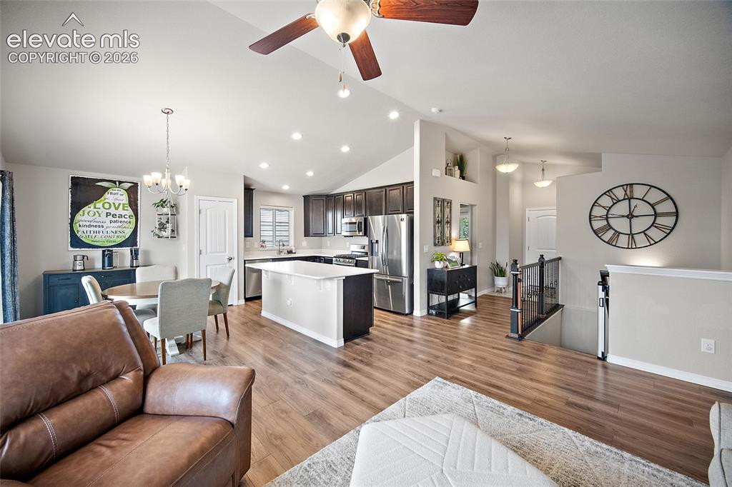 Image 5 of 49: Open-concept living space with vaulted ceilings, wood-finish flooring, and