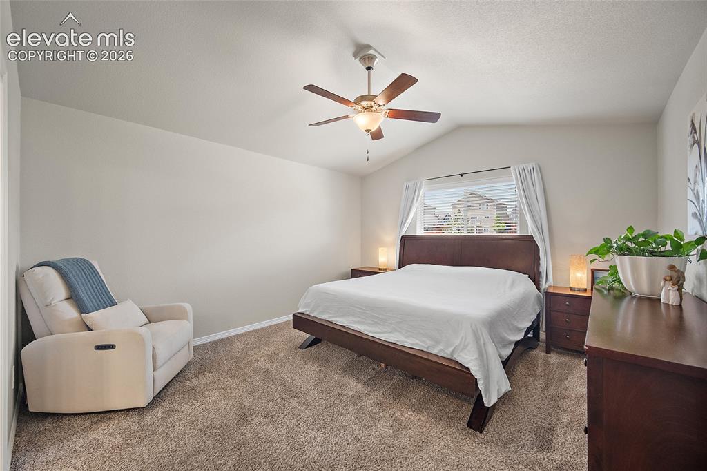 Image 6 of 49: Carpeted bedroom with vaulted ceilings and a ceiling fan