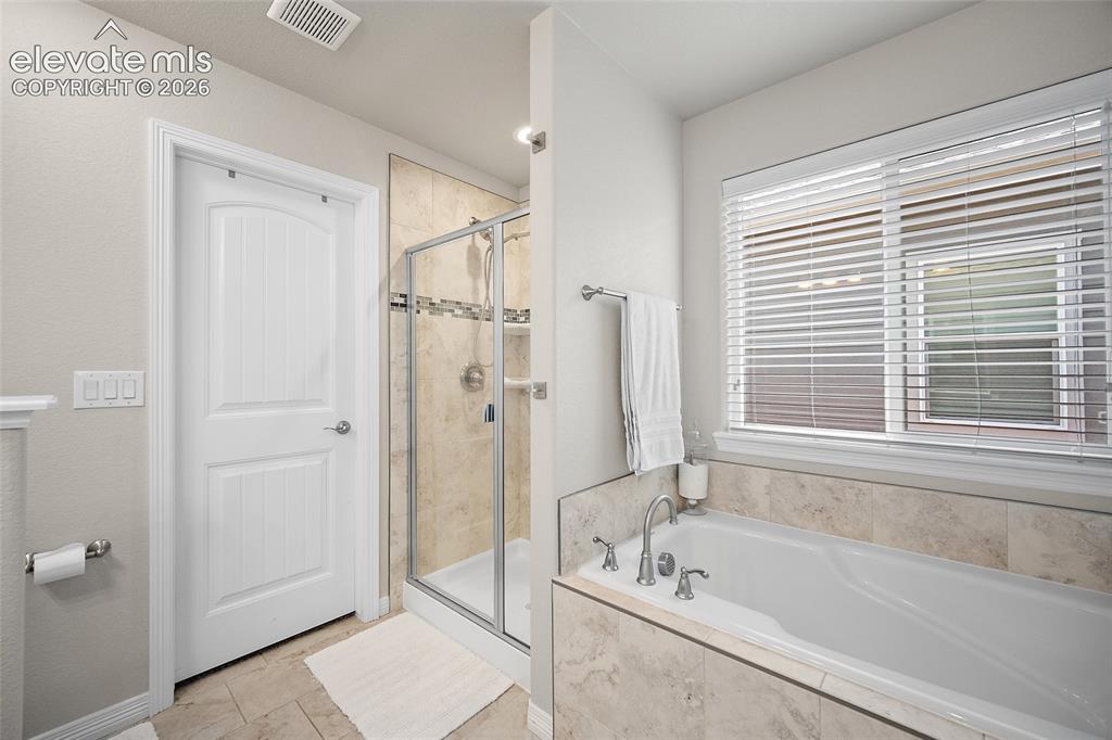 Image 7 of 49: Bathroom featuring a built-in soaking tub with deck-mounted faucet, a separ