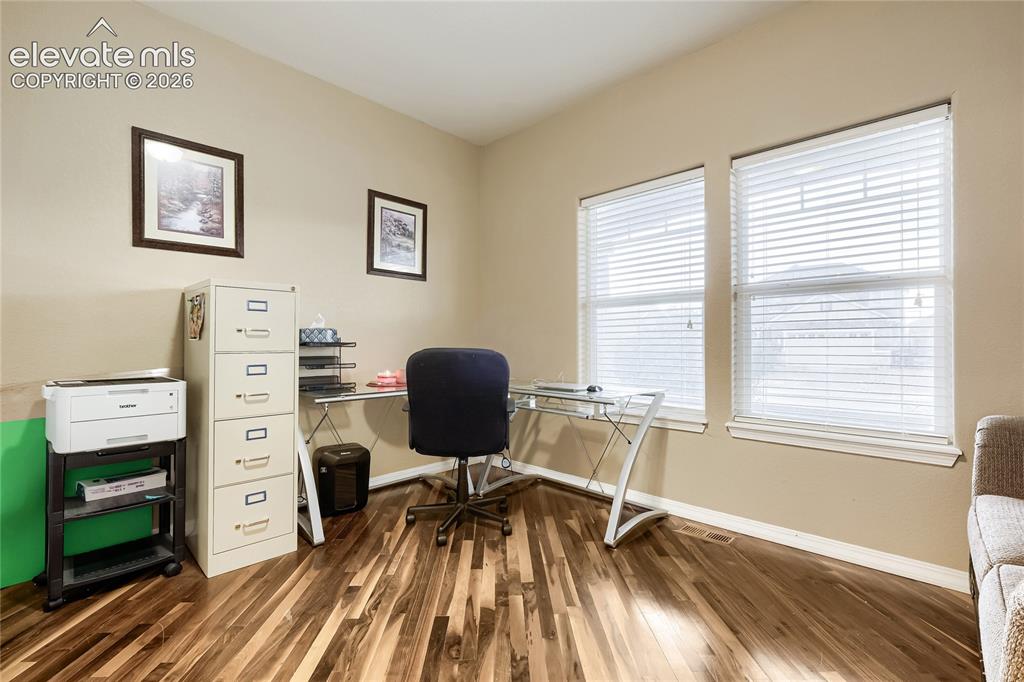 Image 10 of 32: Main level bedroom/office featuring wood floors and has an adjoining 3/4 ba