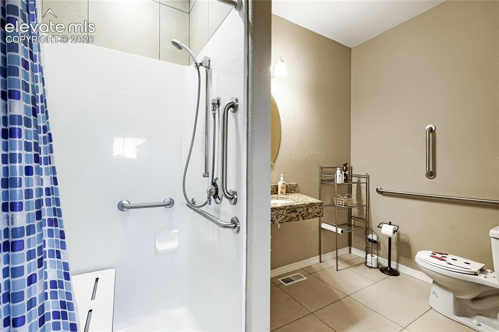 Image 11 of 32: This bath adjoins the main level bedroom-shower with grab bars and built-in