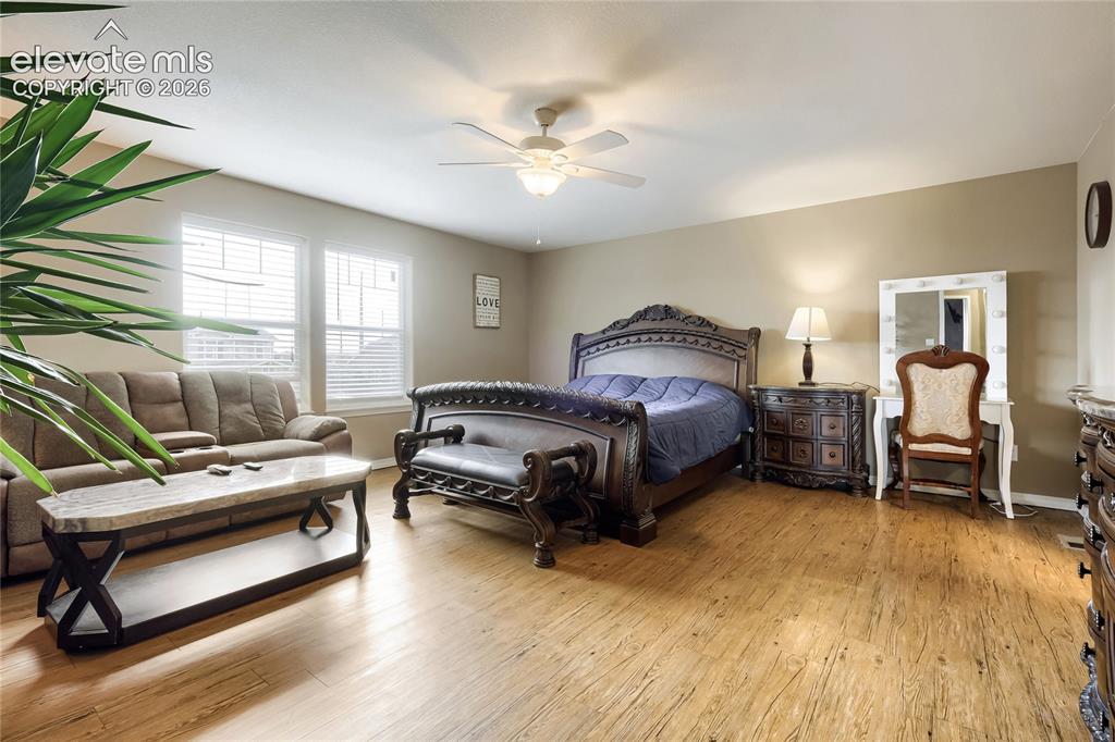 Image 13 of 32: Spacious primary bedroom featuring wood-finish flooring, sitting area, neut