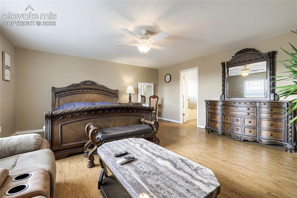 Image 14 of 32: Primary bedroom featuring wood-finish flooring, a sitting area and large wa
