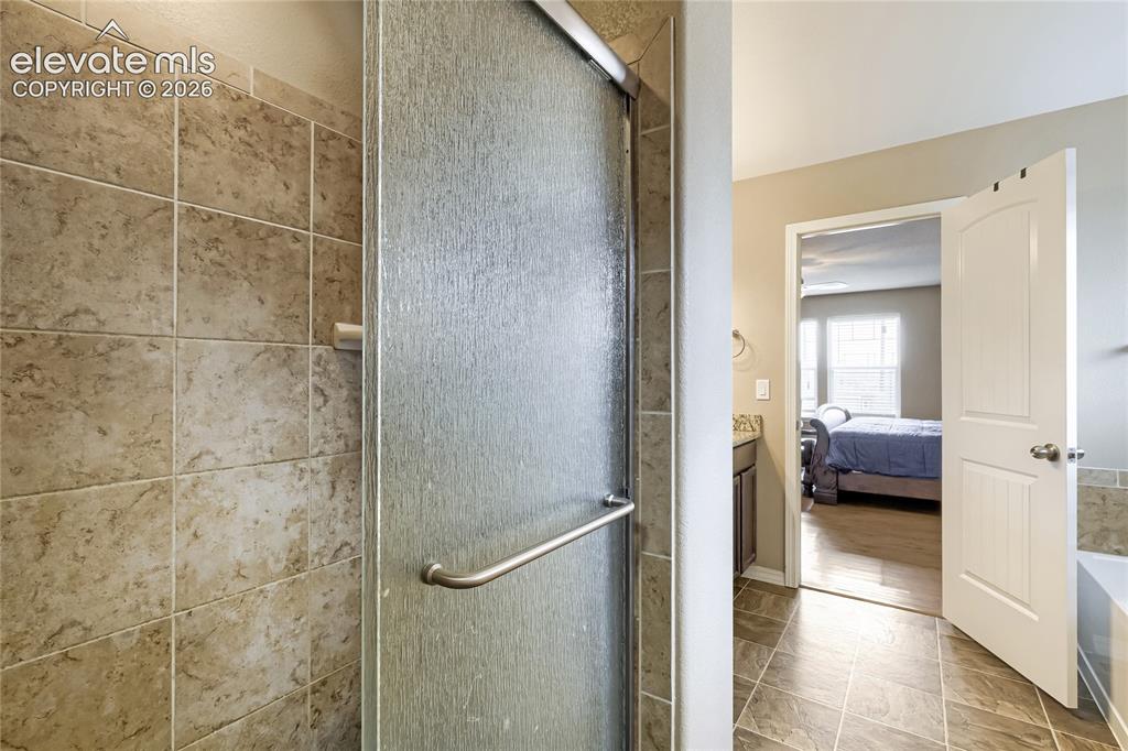Image 16 of 32: Walk-in shower featuring a textured glass door and large format tile surrou