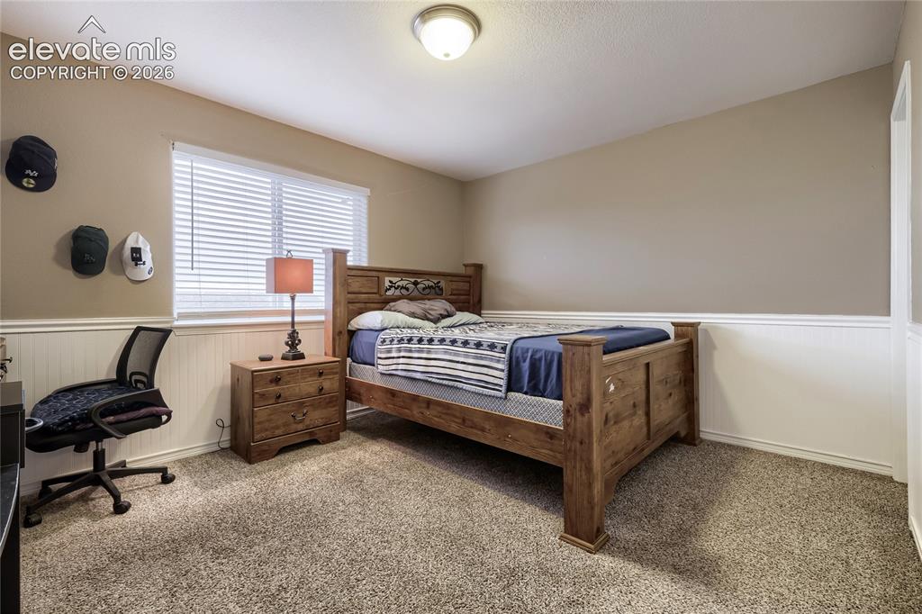 Image 18 of 32: 3rd upper-level bedroom room featuring Wainscoting and walk-in closet