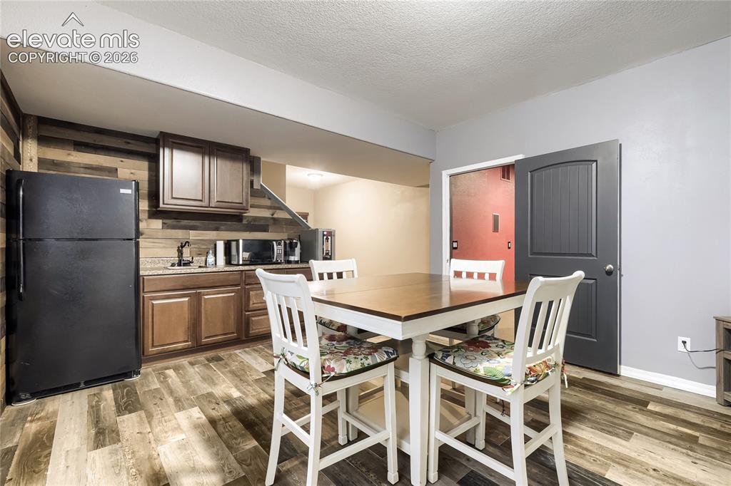 Image 25 of 32: Lower-level wet bar featuring wood-look paneling, a stainless steel sink, w