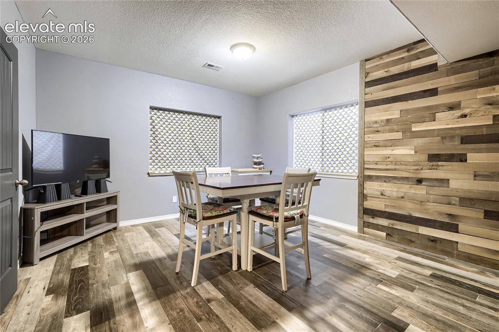 Image 26 of 32: Wet bar featuring wood-finish flooring, a decorative accent wall with varie