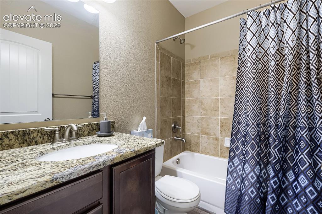Image 27 of 32: Basement full bathroom featuring a dark wood-finish vanity with a granite c