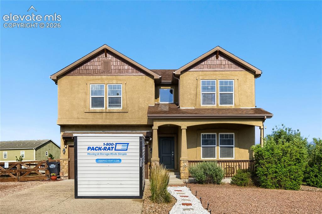 Image 28 of 32: Two-story stucco property featuring a covered front porch with stone-wrappe