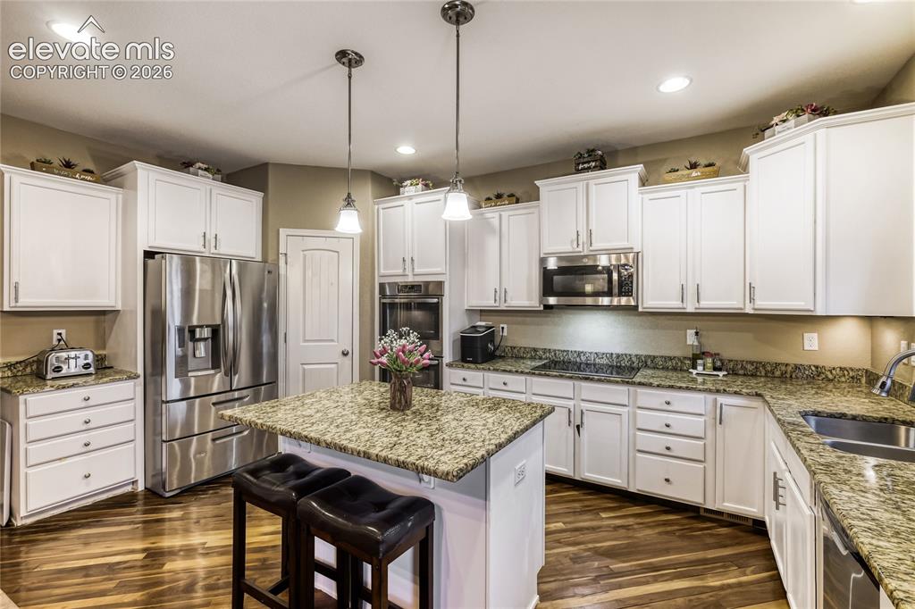 Image 5 of 32: Kitchen featuring a central island, white cabinetry, integrated stainless s