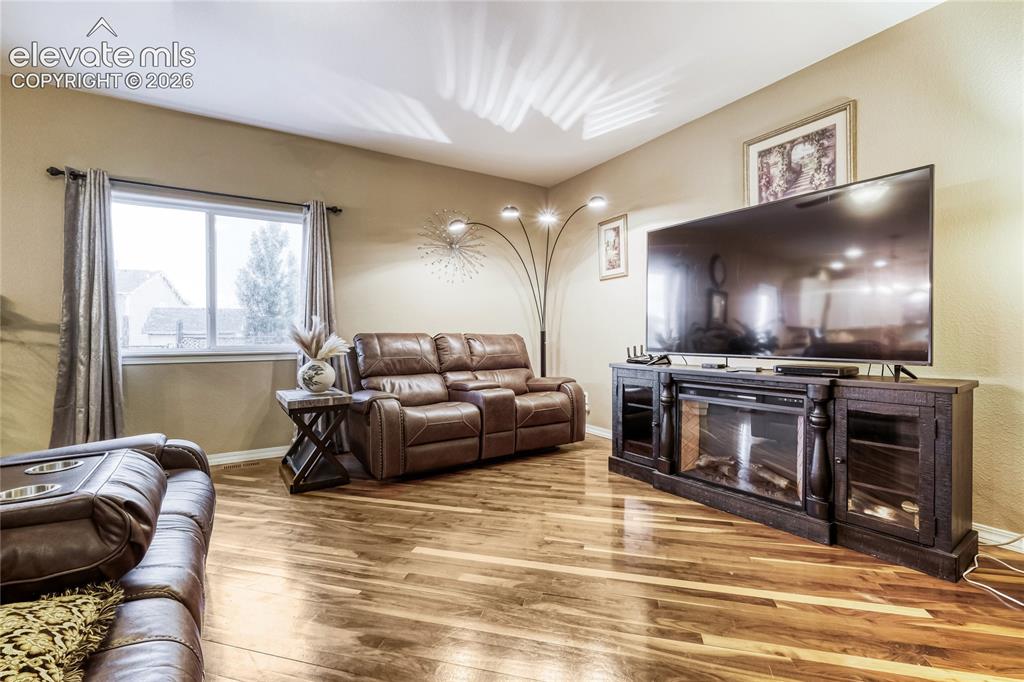 Image 8 of 32: Spacious living area featuring wood flooring, a large picture window, and n