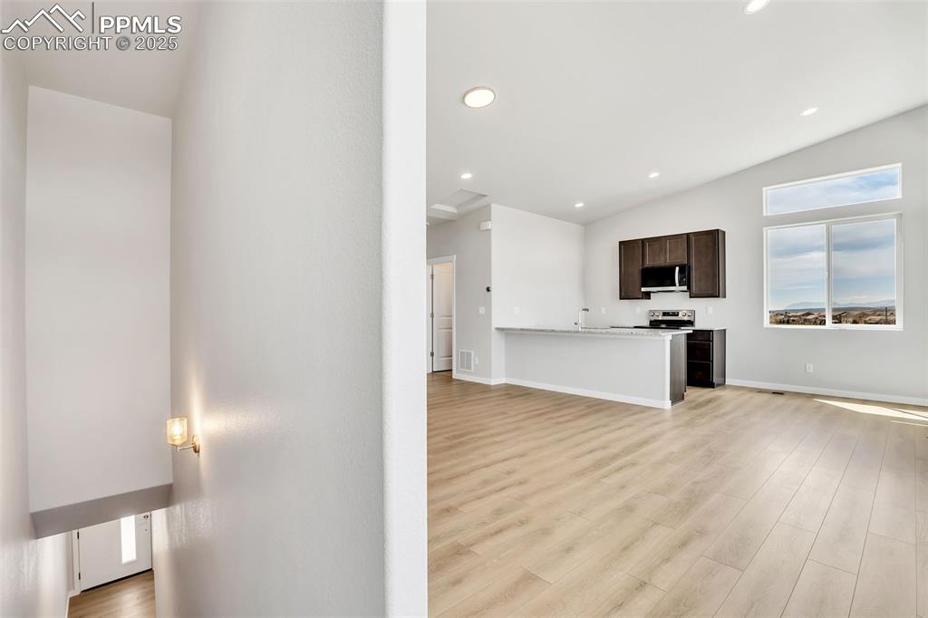 Image 19 of 29: Unfurnished living room featuring lofted ceiling, baseboards, recessed ligh