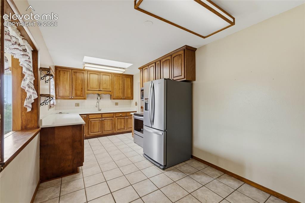 Image 12 of 43: Kitchen featuring wood cabinetry, white tile flooring, white countertops, a