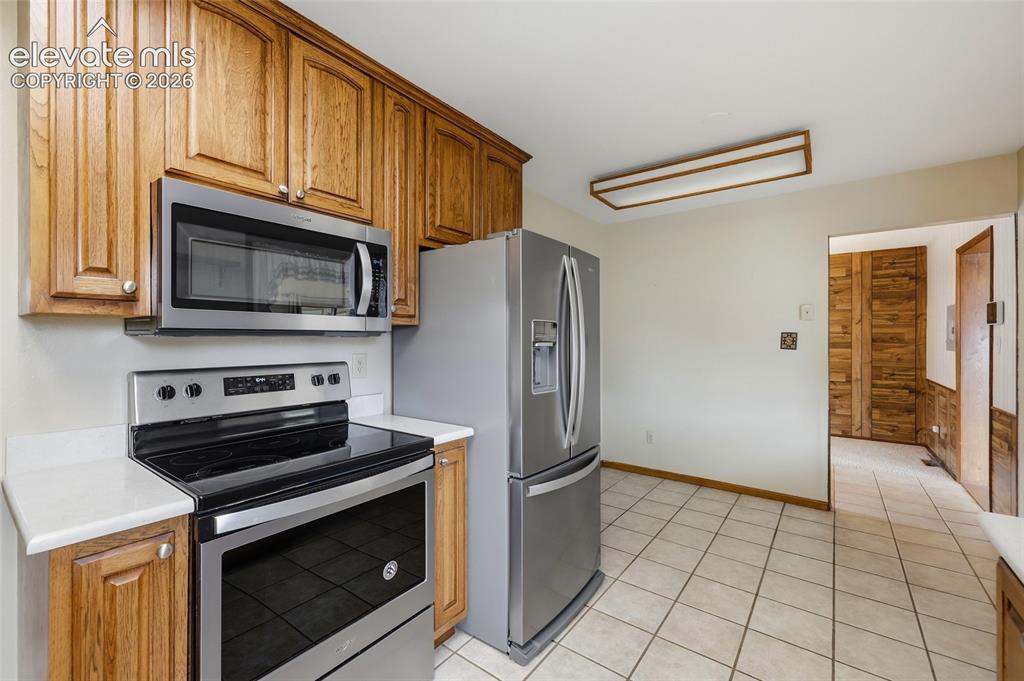 Image 13 of 43: Kitchen featuring stainless steel appliances, wood cabinetry, light-toned c