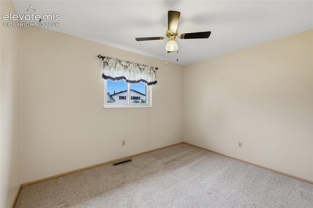 Image 17 of 43: Neutral wall paint, ceiling fan with integrated lighting, window with a dec