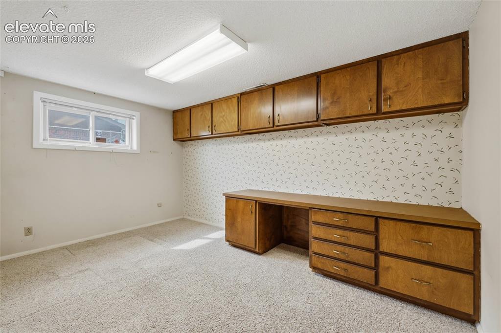 Image 22 of 43: Built-in wood-finish cabinetry, integrated desk space, upper storage cabine