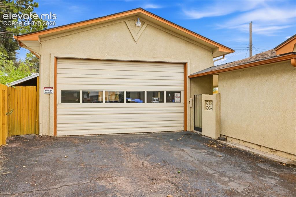 Image 28 of 43: Stucco exterior building with a roll-up garage door featuring windows, an a