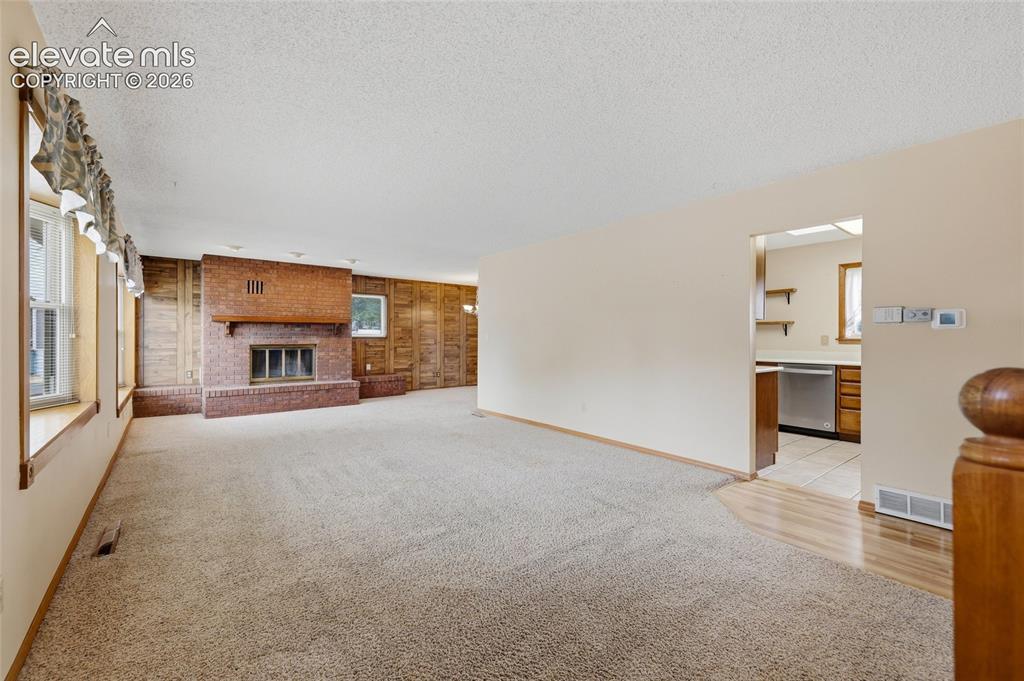 Image 4 of 43: Spacious living area featuring a prominent brick fireplace, multiple window