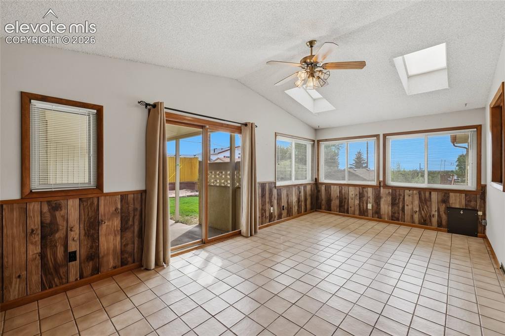 Image 6 of 43: Vaulted ceiling with dual skylights, a ceiling fan, and ceramic tile floori