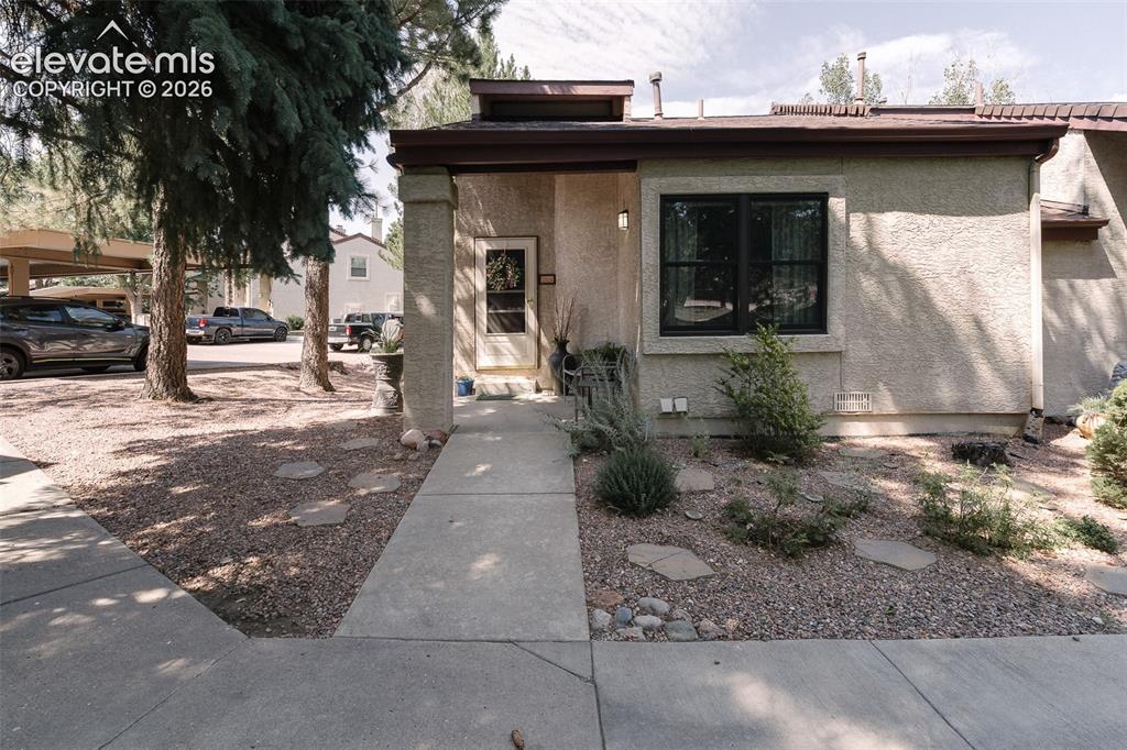 Image 4 of 27: Low maintenance xeriscaped yard and covered front porch.