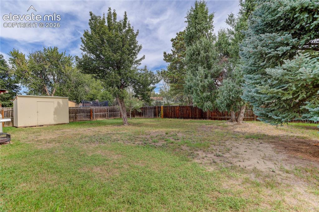 Image 25 of 26: Fully fenced yard w/ mature trees