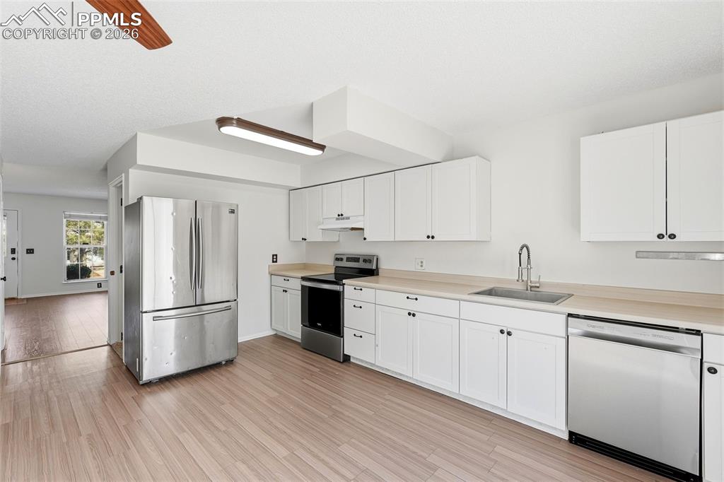 Image 10 of 44: Kitchen featuring stainless steel appliances, light countertops, white cabi