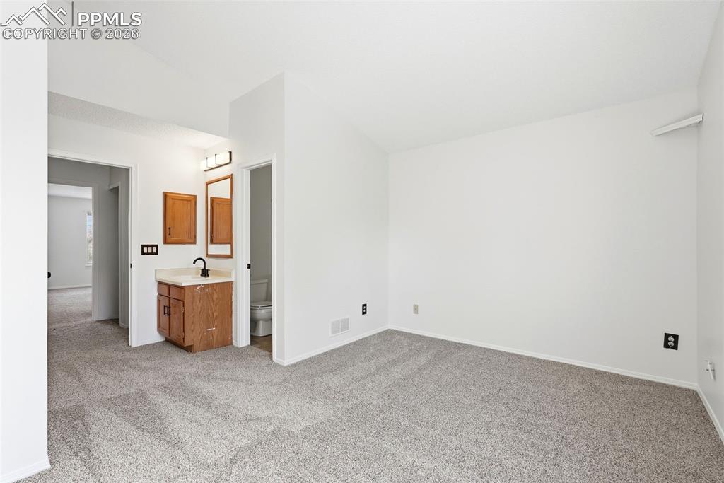 Image 20 of 44: Unfurnished bedroom with lofted ceiling, light colored carpet, and connecte