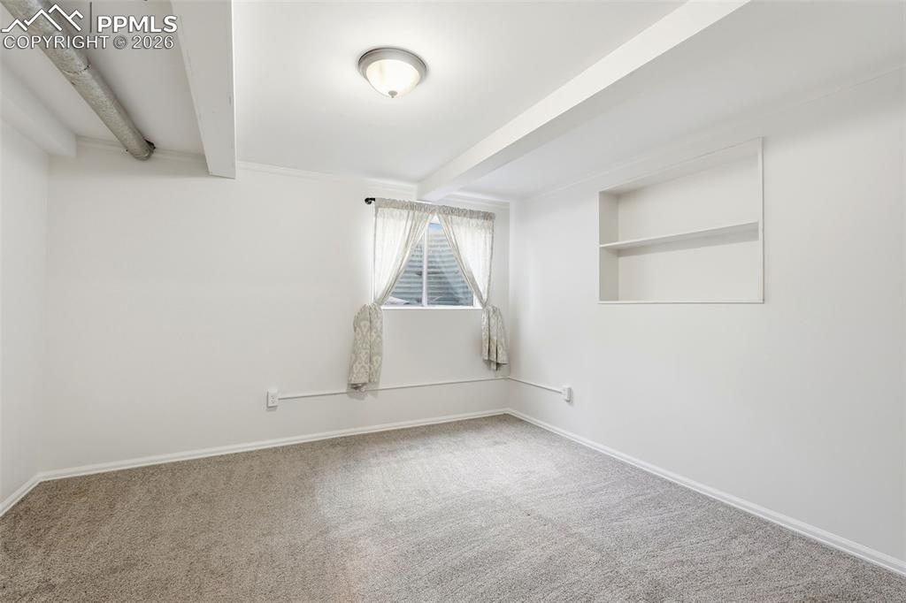 Image 33 of 44: Unfurnished room with light carpet and beamed ceiling