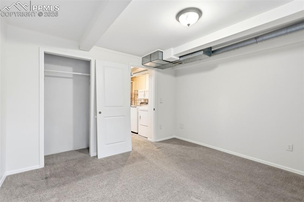 Image 35 of 44: Unfurnished bedroom with washing machine and dryer, light carpet, a closet,