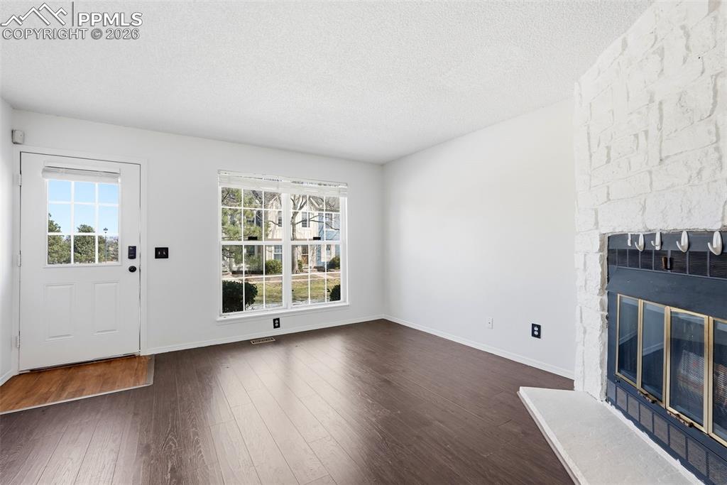 Image 5 of 44: Unfurnished living room with dark wood-type flooring, a fireplace, and a te