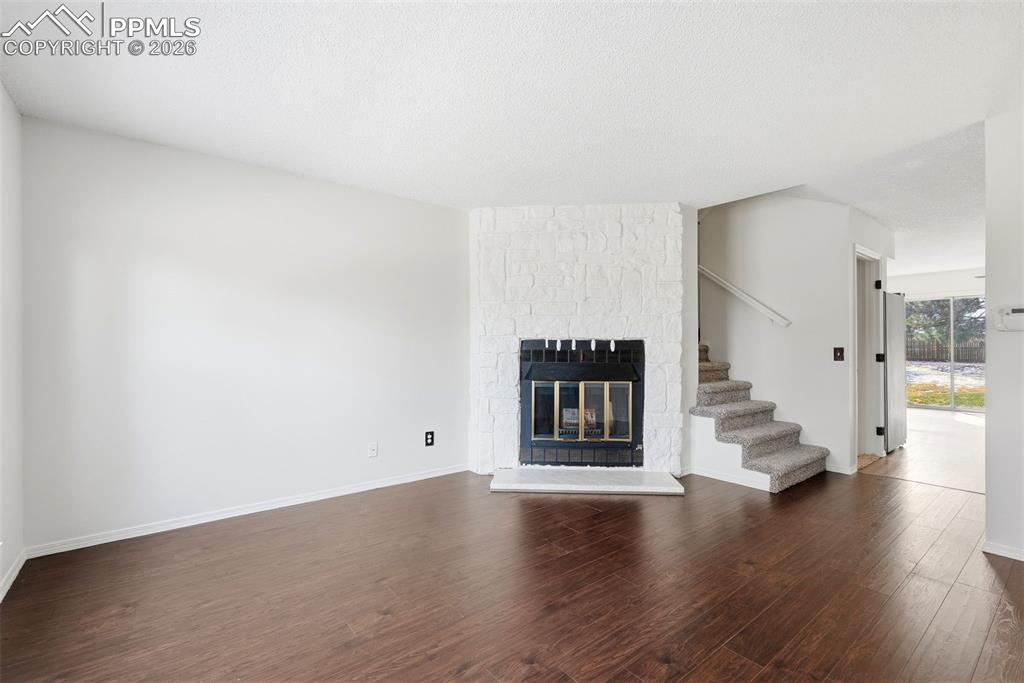 Image 6 of 44: Unfurnished living room with dark wood finished floors, a fireplace, and a 