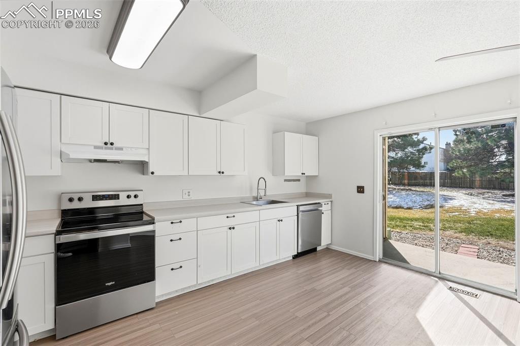 Image 9 of 44: Kitchen with stainless steel appliances, white cabinetry, light countertops