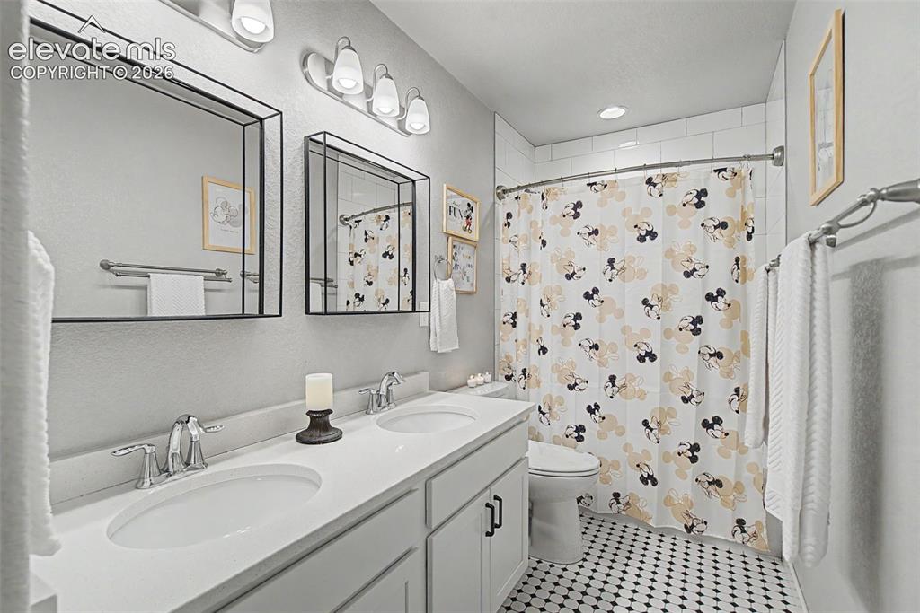 Image 29 of 40: Spacious double quartz vanity and classic real tile flooring. 