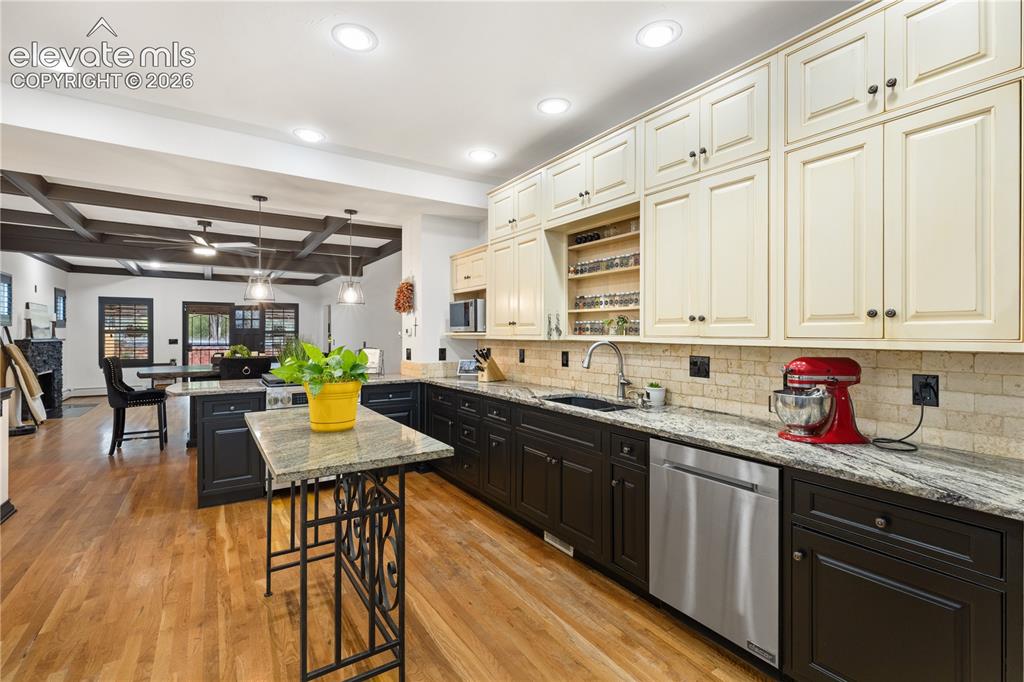 Image 23 of 45: Gourmet kitchen featuring wood-finish flooring, two-tone cabinetry with bla