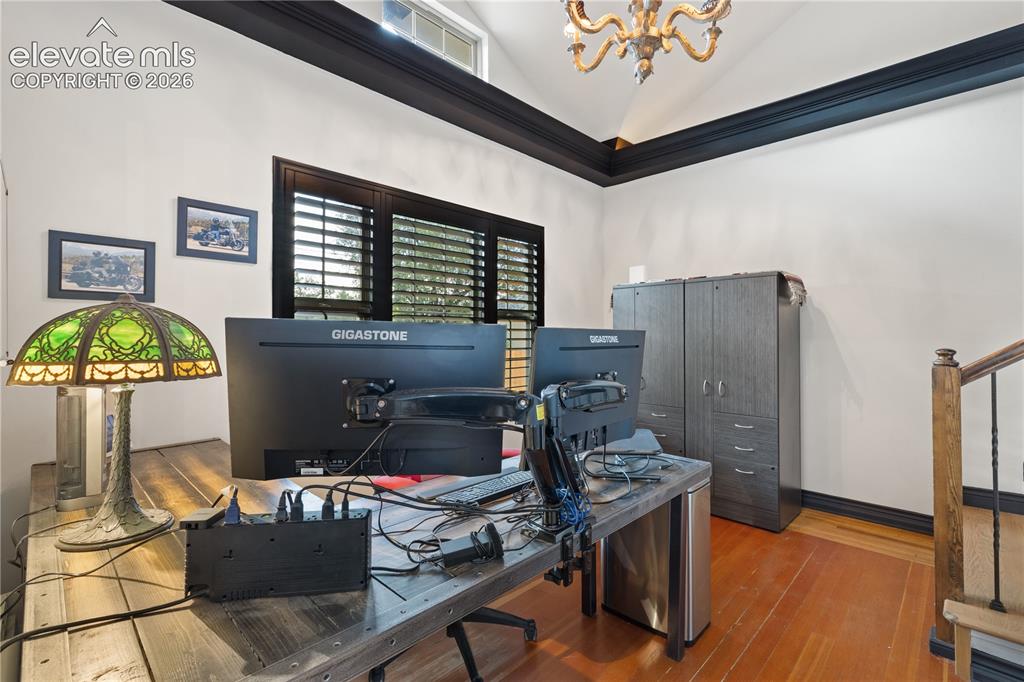 Image 26 of 45: Vaulted ceiling with crown molding, natural wood flooring, window with inte