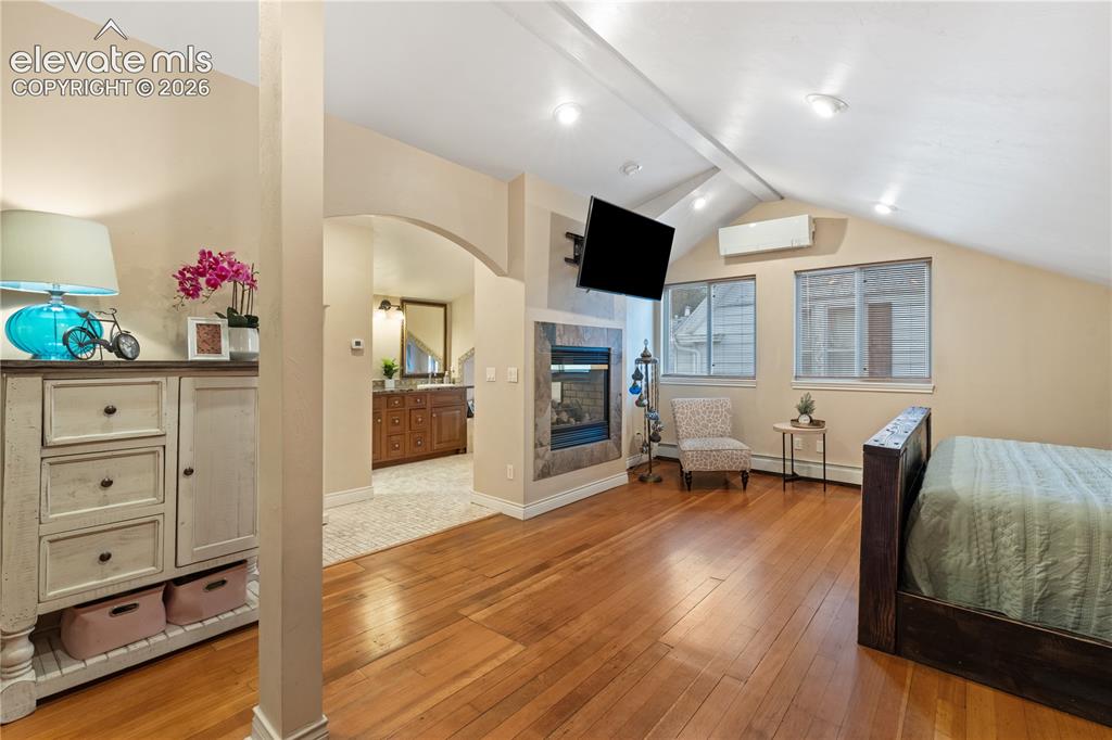 Image 29 of 45: Hardwood flooring throughout the sleeping area, featuring a built-in firepl
