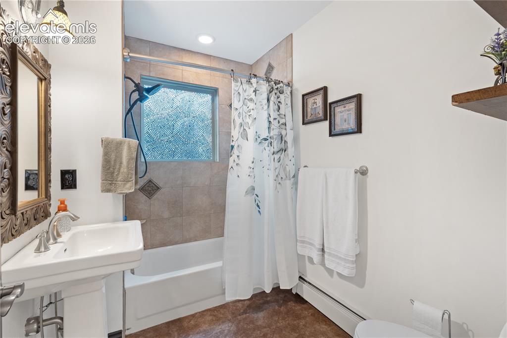Image 37 of 45: Bathroom featuring a pedestal sink, tub with a shower fixture, and a tiled 
