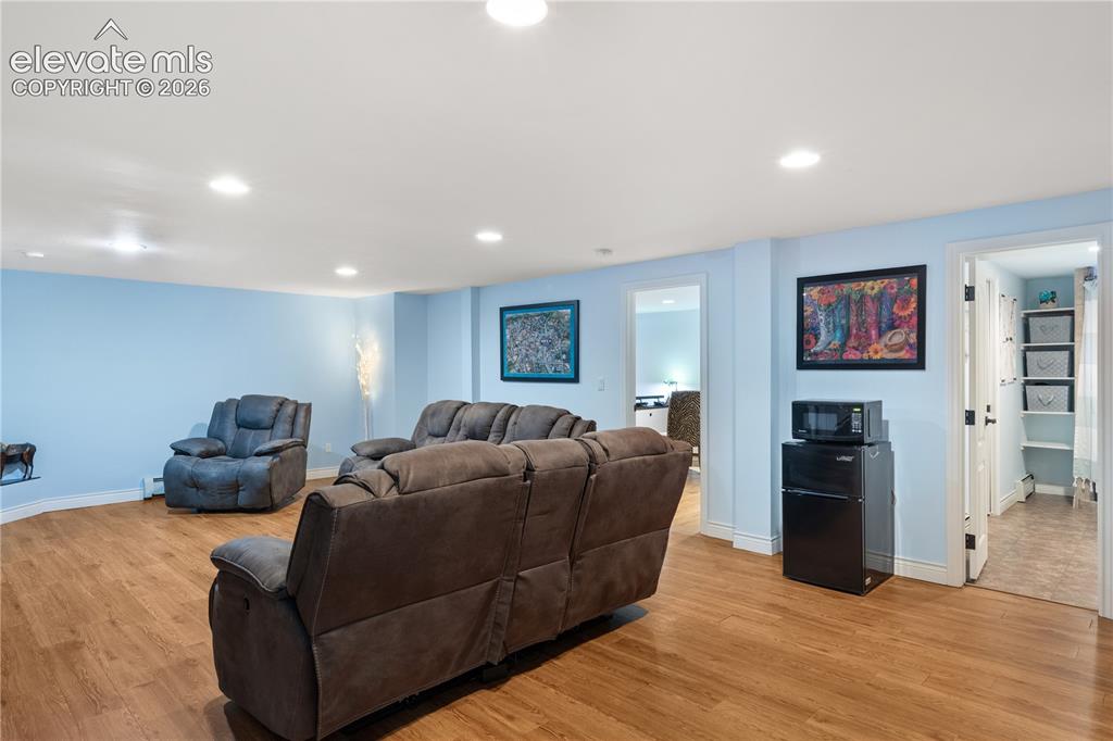 Image 39 of 45: Recessed lighting illuminates the spacious room featuring wood-finish floor