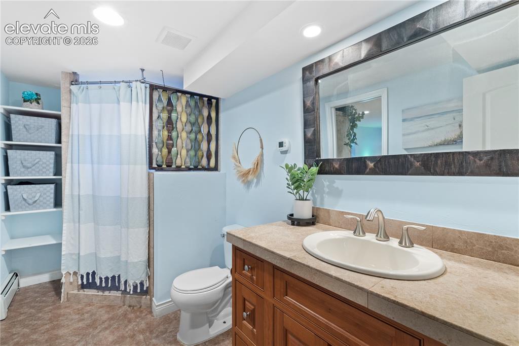 Image 43 of 45: Bathroom featuring a wood vanity with an integrated sink, a tiled counterto