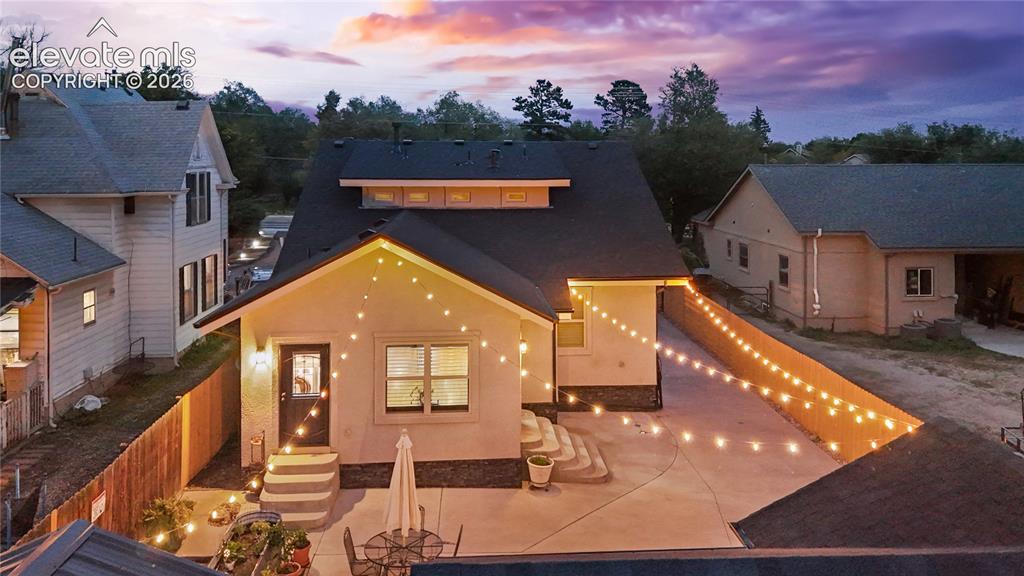 Image 6 of 45: Rear exterior featuring a concrete patio, string lighting, and a dark aspha