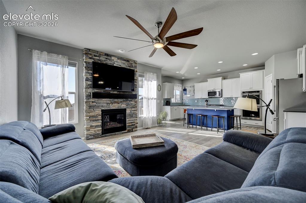 Image 11 of 48: Open-concept living area featuring a stacked stone fireplace with a built-i