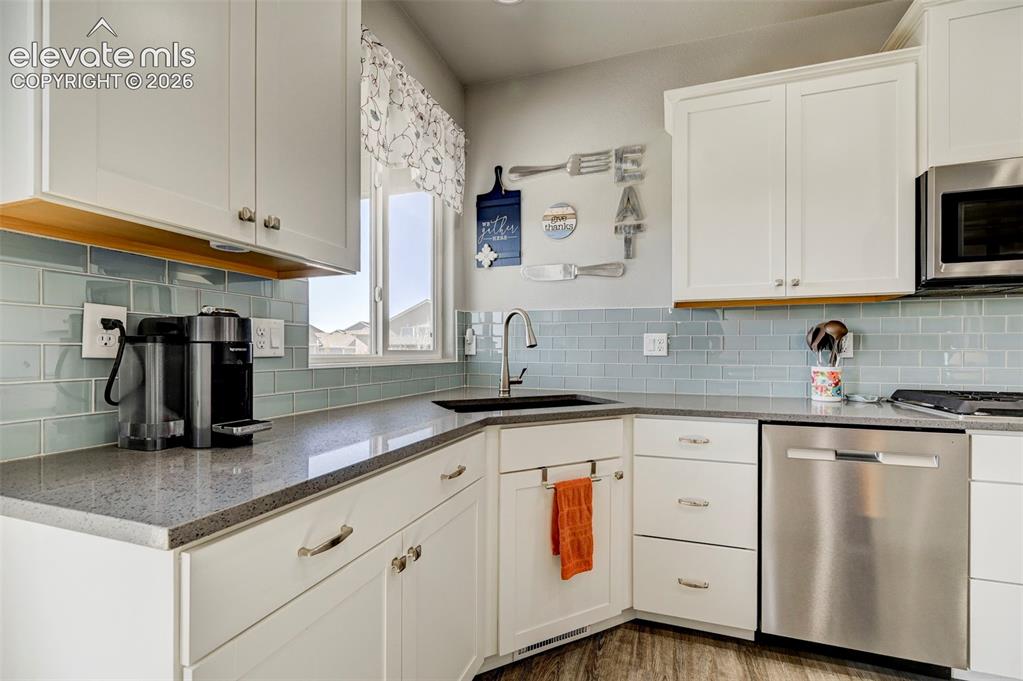 Image 16 of 48: Kitchen featuring white cabinetry, grey speckled countertops, a light blue