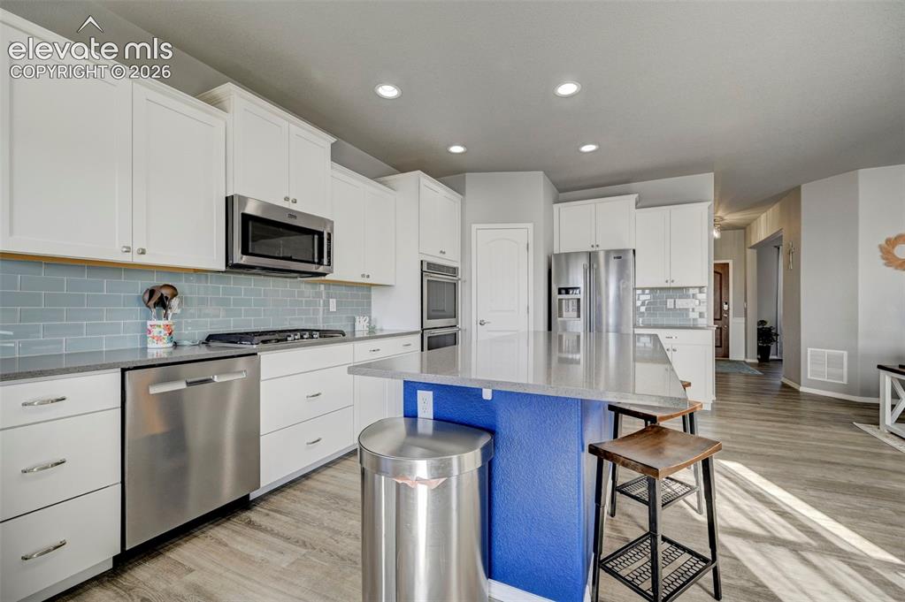 Image 17 of 48: Modern kitchen featuring a central island with a contrasting blue base, lig